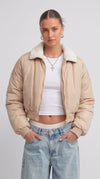 Front full view of premium light beige silk cotton cropped jacket highlighting the clean short waist-length cut and minimalist center zip closure.