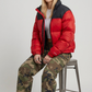 High-street urban lifestyle photography featuring a modern winter outfit styled seamlessly with a vibrant red and black streetwear bubble jacket.