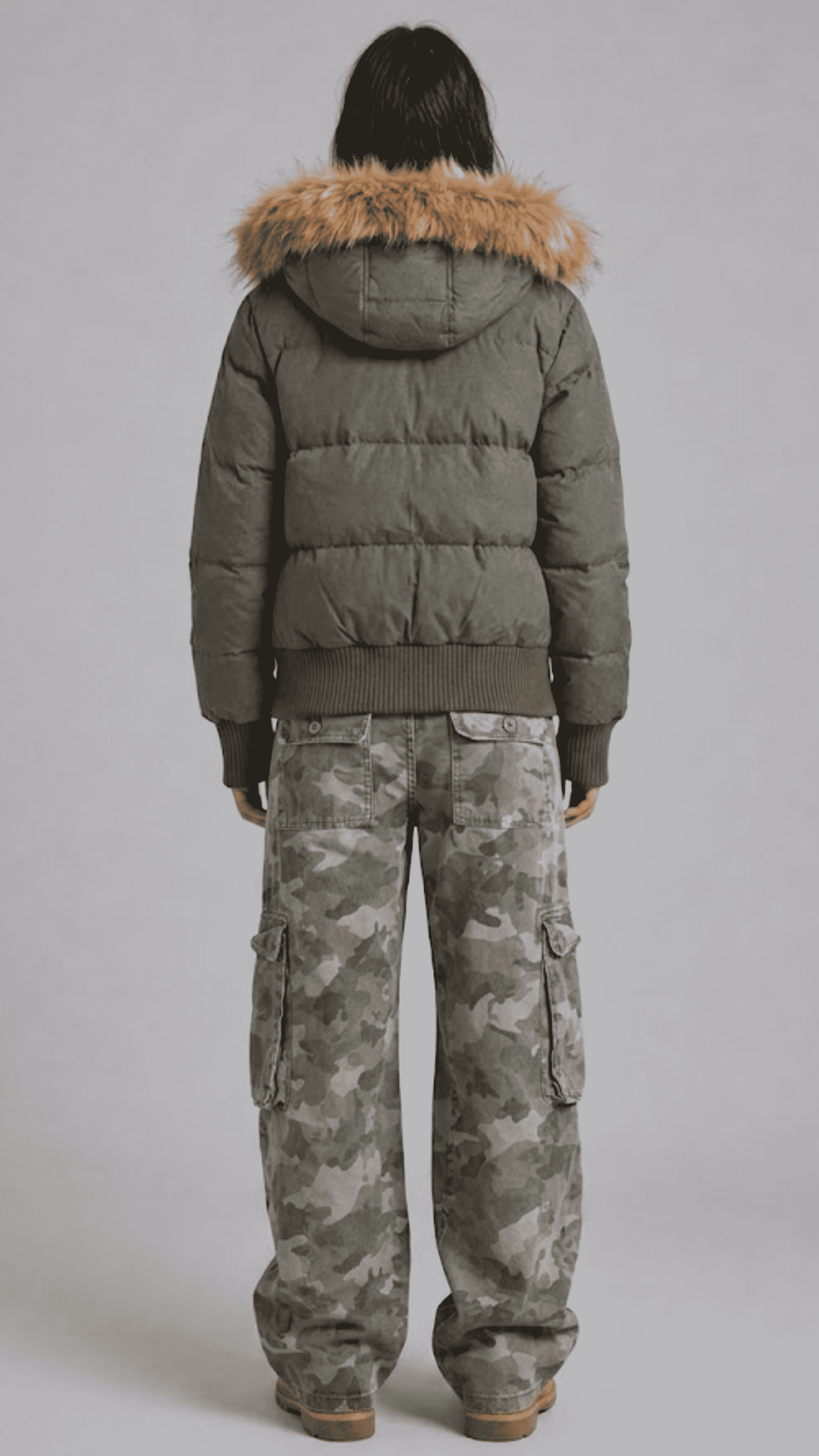 Rear view of loose fit olive puffer coat displaying broad horizontal quilted baffling and voluminous fur-trimmed hood
