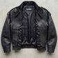 A black leather jacket with a zippered front and ribbed collar, laid flat on a textured gray concrete surface. The brand name 'JACKERO' is visible on the inner neck label.
