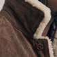 Close-up of a brown coat with white fur lining and a button.