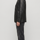 Sophisticated black leather blazer styled open over a monochrome dark outfit, perfect for urban evening luxury aesthetics.