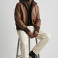 Premium men's urban lifestyle lookbook photography focusing on a sophisticated winter style utilizing a sleek mahogany brown leather bomber coat.