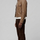 Side angle profile view focusing on the heavy-duty metallic hardware zipper and tonal elastic ribbed cuffs of the neutral beige outerwear.