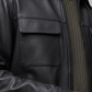 Close-up of a person wearing a black leather jacket with a neutral background