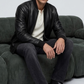 Sophisticated men's urban lifestyle photography showcasing a smart casual winter outfit anchored by a luxury classic black leather bomber coat.