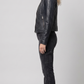 Detailed view of the structured collar lapels, metallic snap buttons, and premium stitching on a women's luxury croc-embossed jacket.