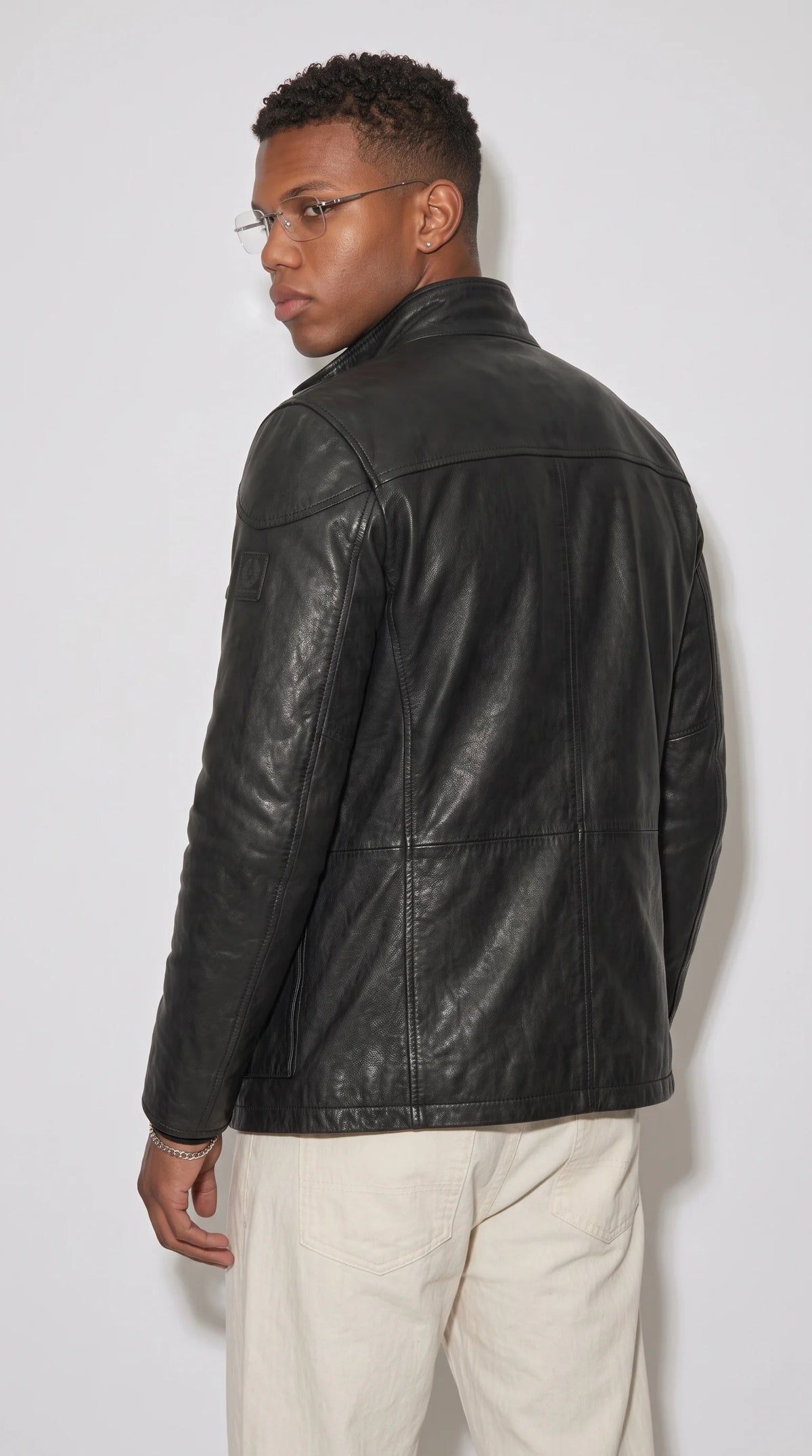 Matte black genuine leather field jacket featuring a convertible stand collar with an adjustable throat latch, carefully aligned leather panels and a streamlined neckline, adding a distinctive utilitarian edge to refined men's outerwear.
