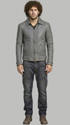 A man wearing a gray leather jacket, dark gray jeans, and brown boots, standing against a solid gray background.