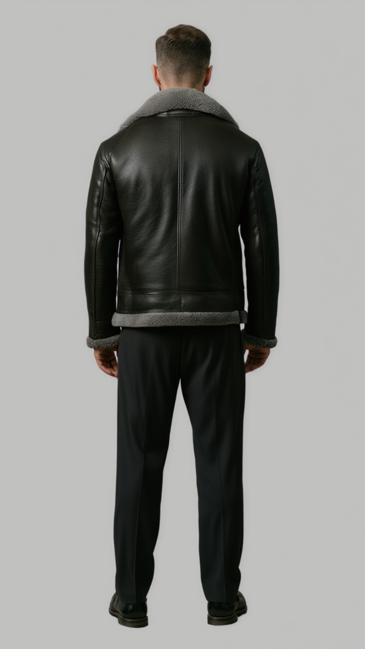 back view of a high-quality black leather winter coat showing precise panels, stitching, and the contrast grey fur collar.