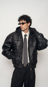 Front view of a men’s black leather hooded jacket styled as urban streetwear, showing the attached hood and sleek dark leather finish for an all-black outfit