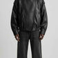 Front view of men wearing black wrap-around high neck leather oversized jacket with asymmetrical snap collar.