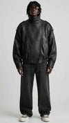 Front view of men wearing black wrap-around high neck leather oversized jacket with asymmetrical snap collar.