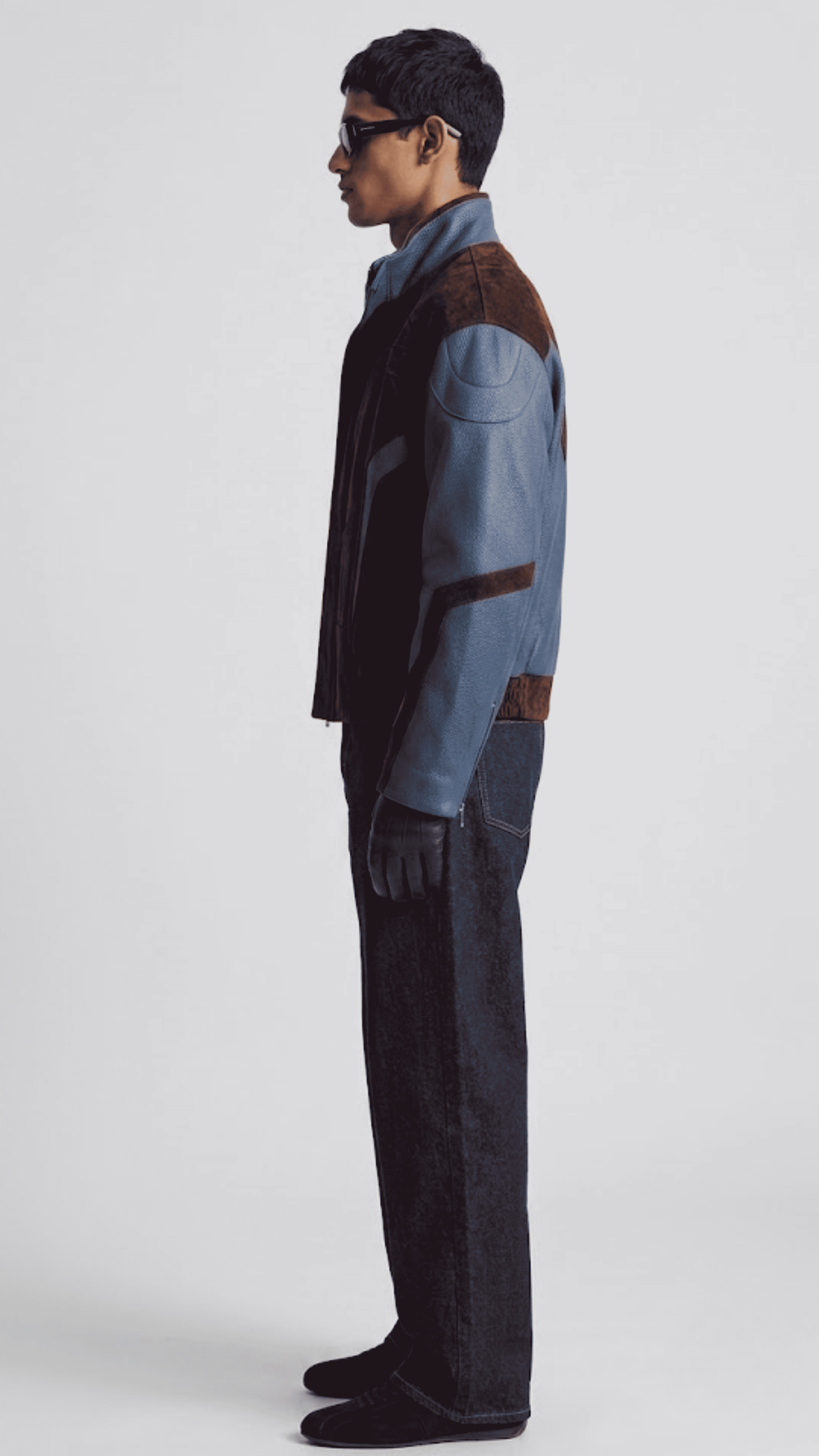 Side view showing waist slash pockets and dark blue leather cuff details on dual-texture streetwear jacket.