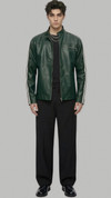 A male model wearing a dark green leather jacket with white stripe details on the sleeves, styled with a black shirt, black trousers, and black shoes, set against a solid gray background.