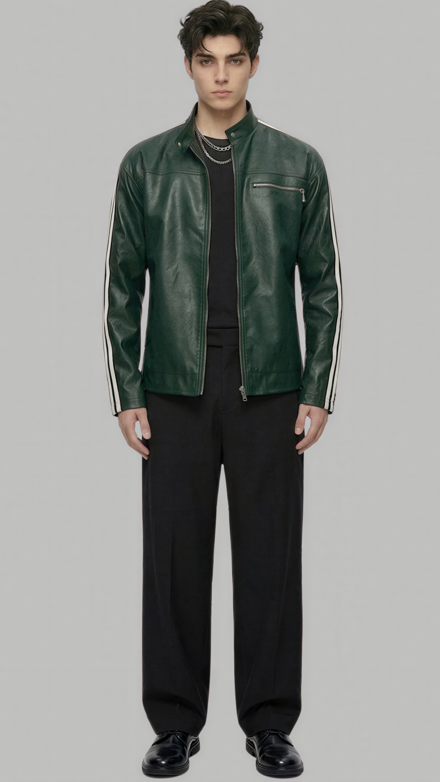 A male model wearing a dark green leather jacket with white stripe details on the sleeves, styled with a black shirt, black trousers, and black shoes, set against a solid gray background.