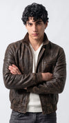 Men's distressed dark brown leather bomber jackero jacket with snap collar and ribbed hem, worn over white knit v-neck sweater
