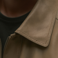 Close-up of a brown leather jacket collar on a neutral background