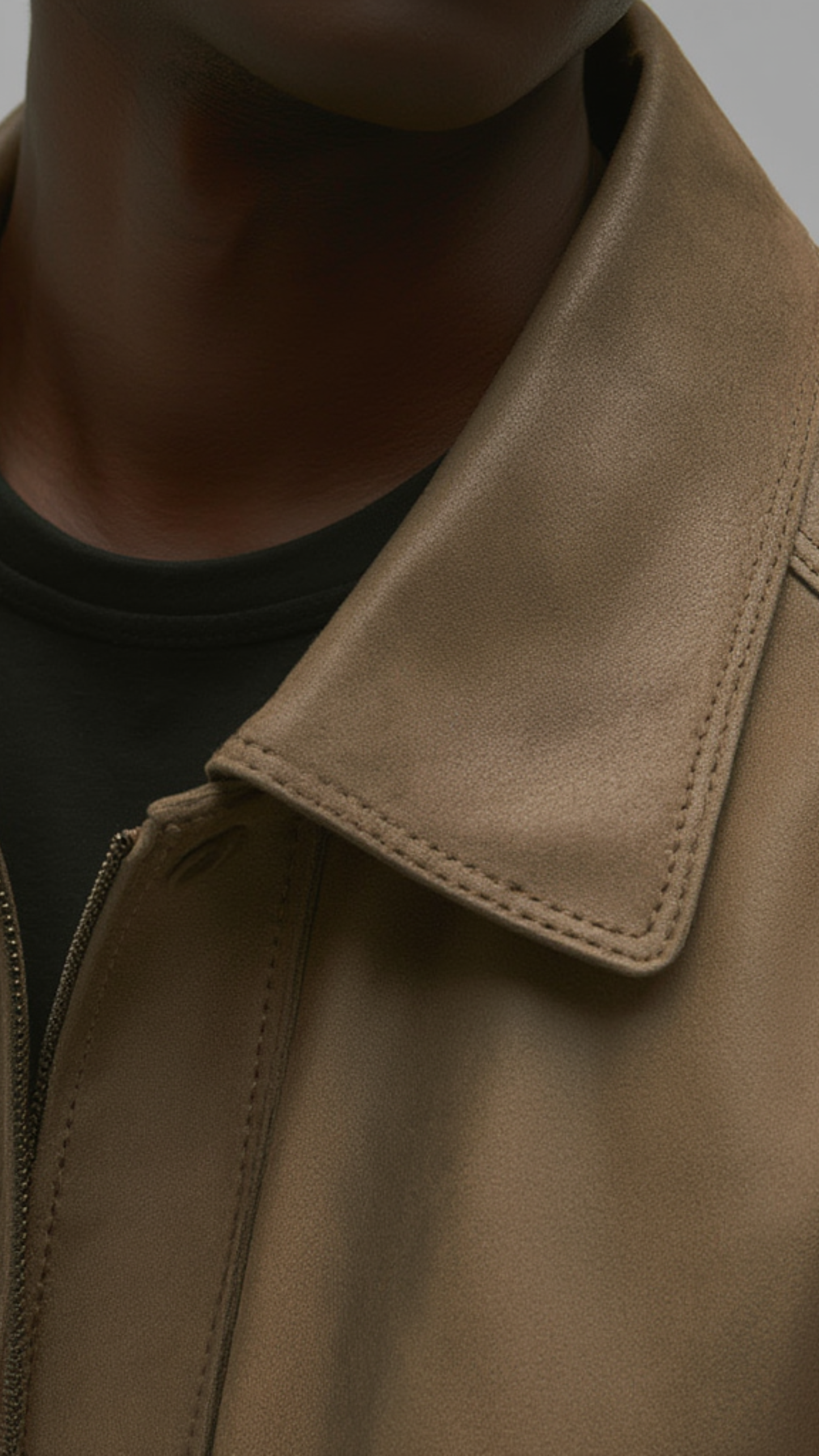 Close-up of a brown leather jacket collar on a neutral background