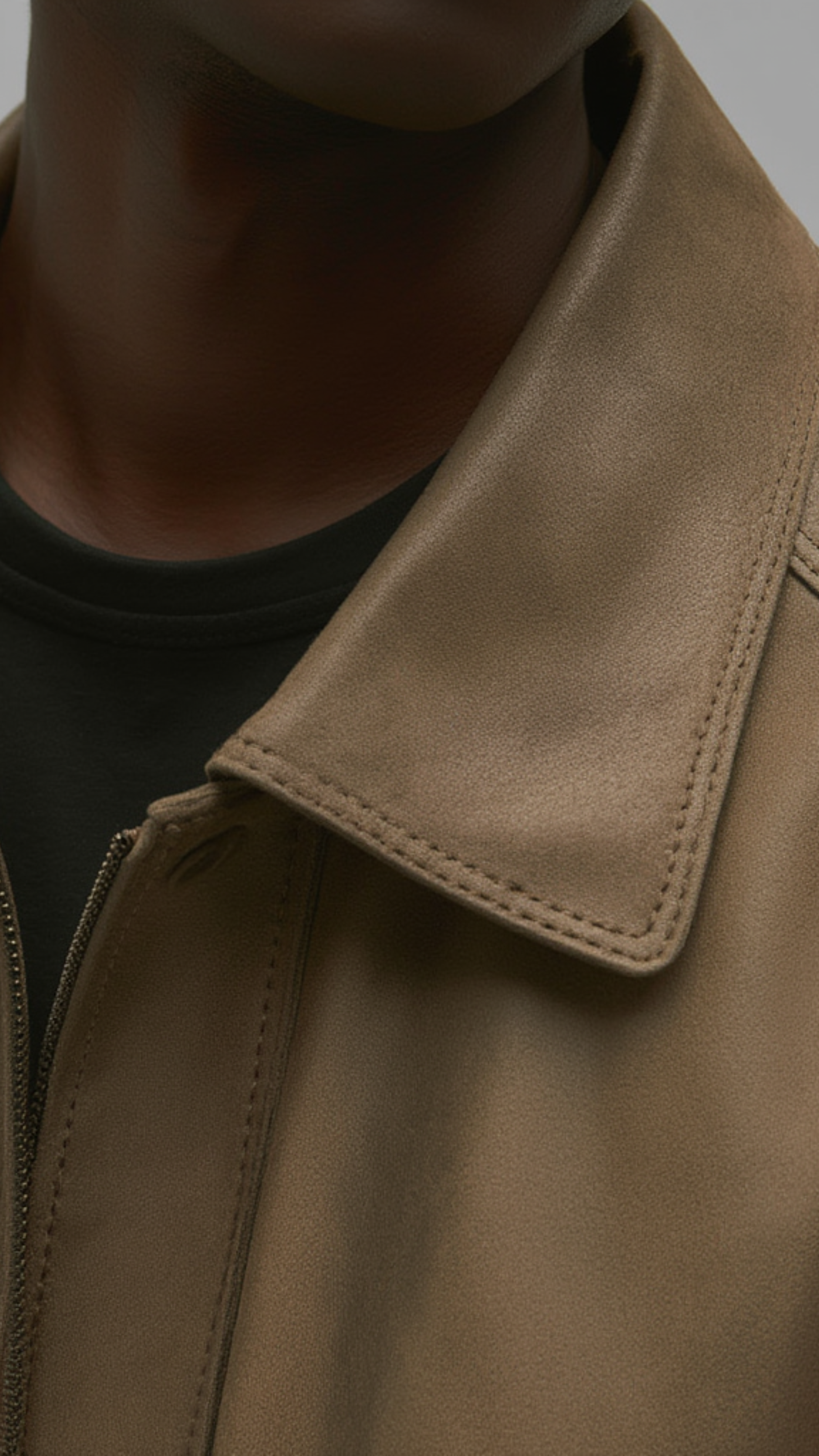 Close-up of a brown leather jacket collar on a neutral background