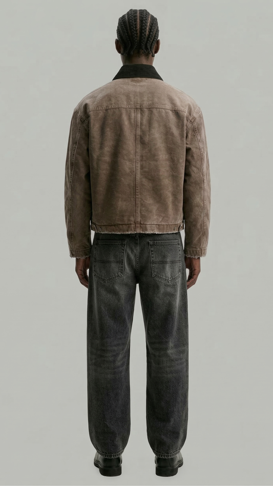 Person wearing a brown corduroy jacket and dark jeans on a plain background