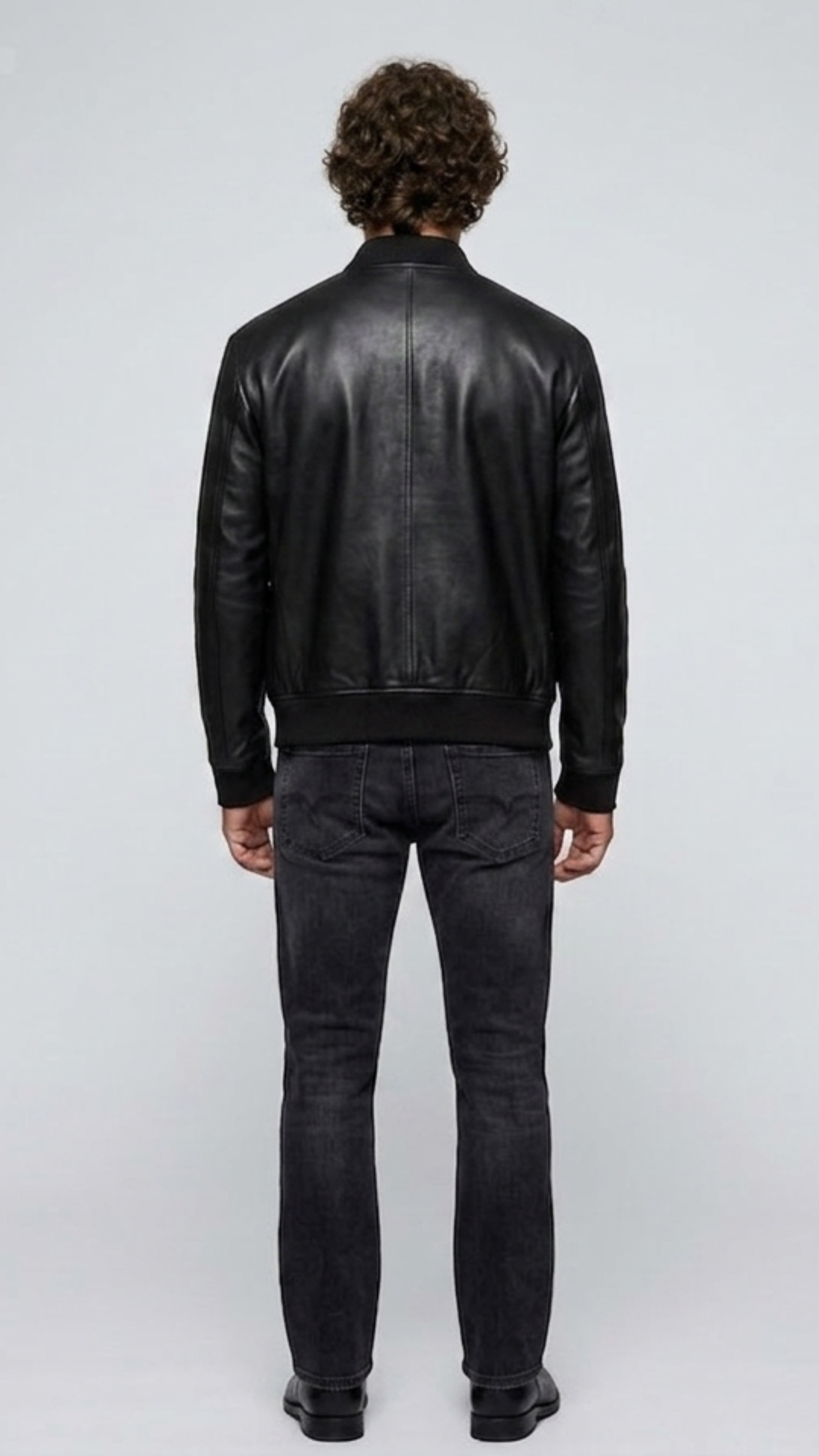 Symmetrical rear view studio shot highlighting the uniform tailoring and smooth premium leather panels of the sleek black flight coat.