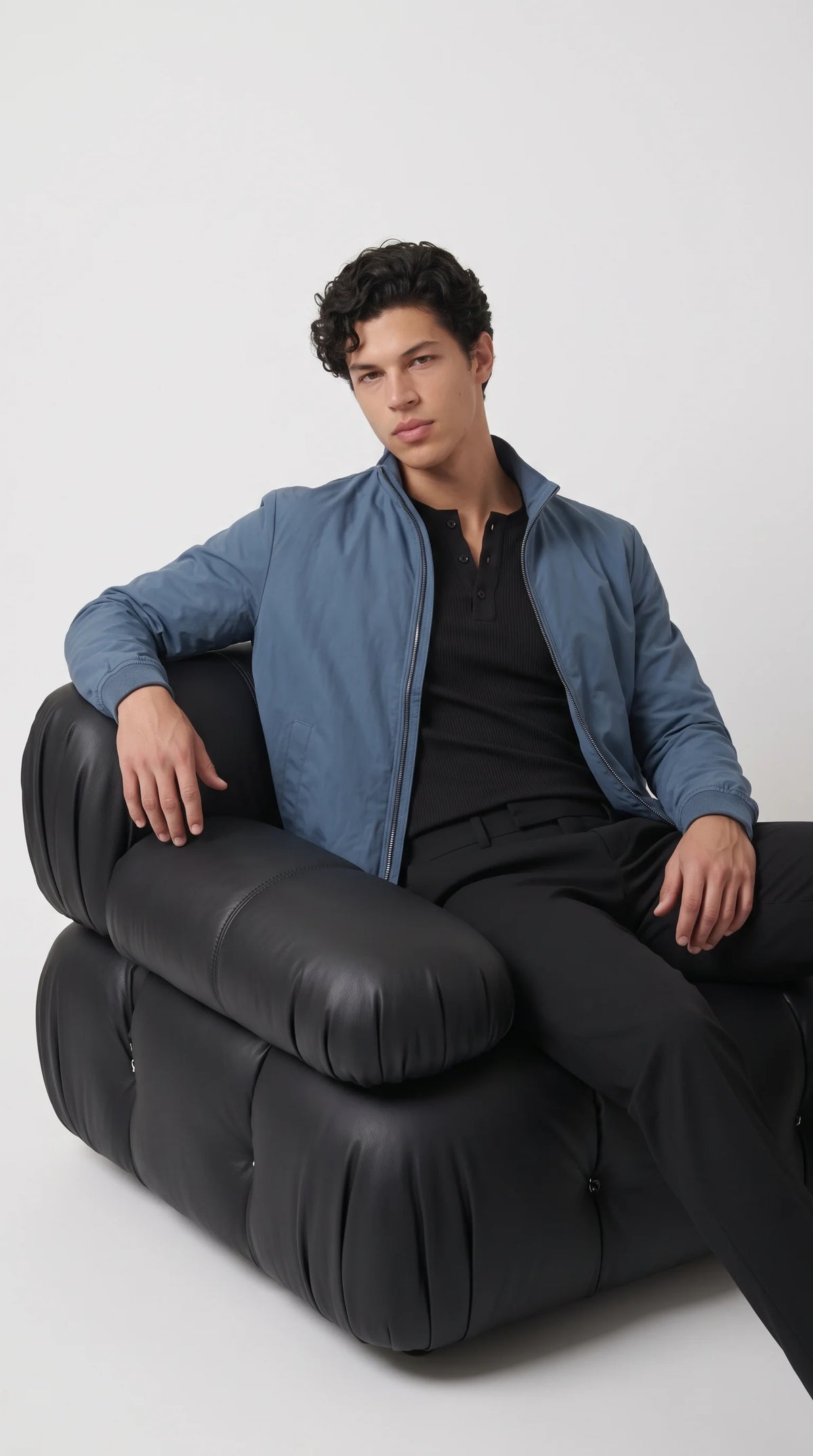 Men’s muted cyan bomber jacket with a low-profile stand collar, full zip fastening, discreet side waist pockets and fitted ribbed cuffs. Its clean proportions create a versatile smart-casual layer that works over a dark knit shirt with tailored trousers, offering a more refined alternative to a traditional sporty windbreaker for modern city dressing.