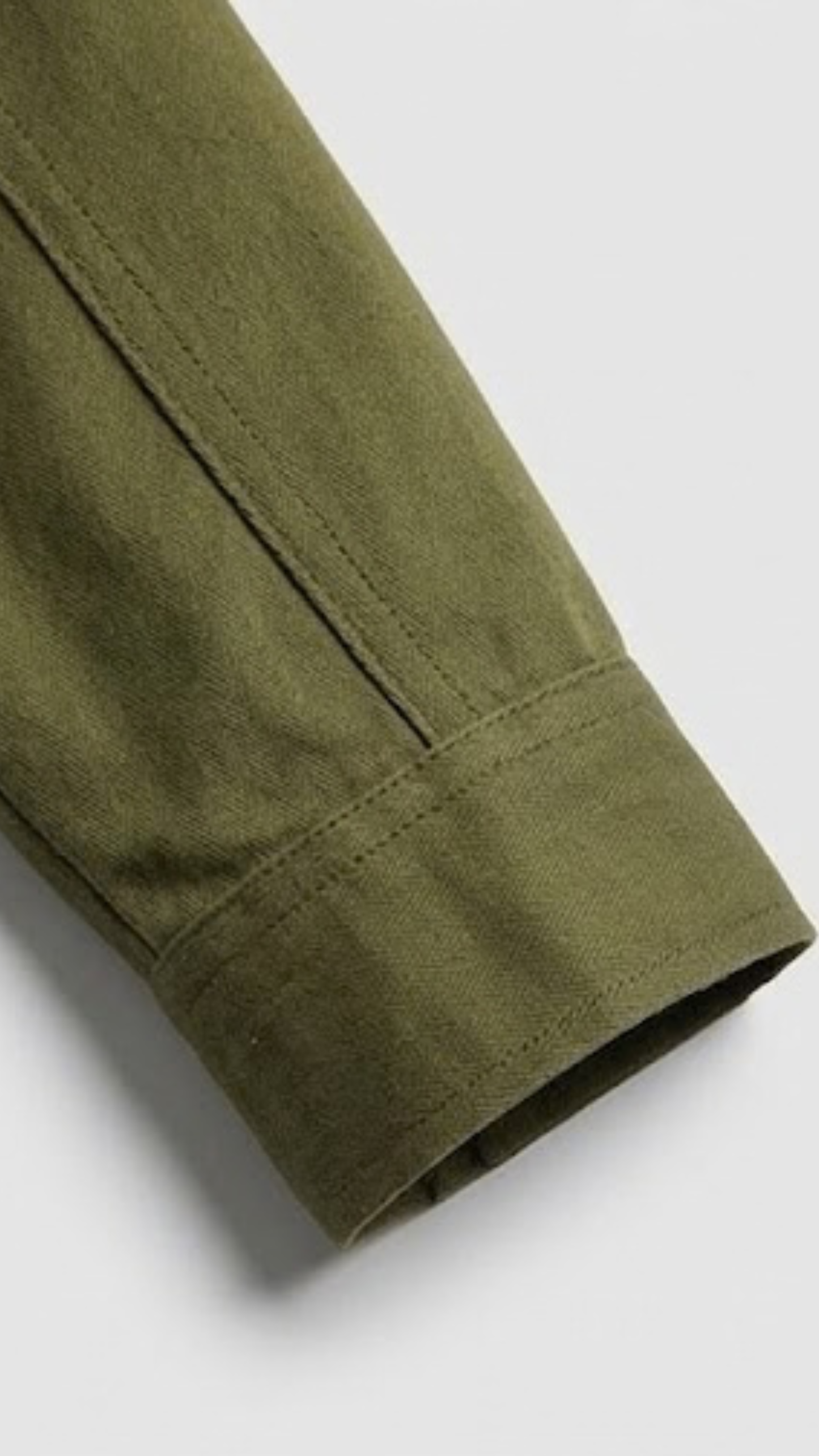 Close-up of a green cotton jacket sleeve on a white background