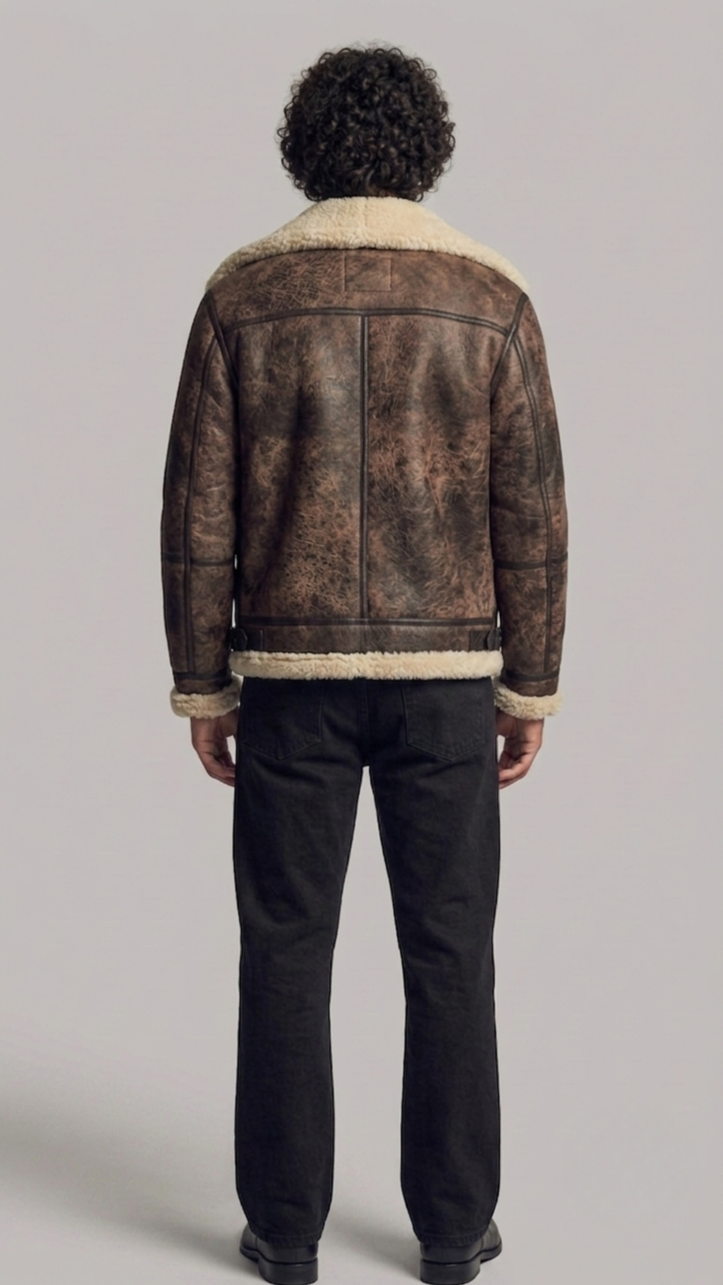 Rear view of a structured dark brown distressed aviator jacket showing the weathered leather texture and clean seams.