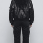 Clean back angle of a structured black leather bomber coat, highlighting the relaxed fit shoulders and tapered ribbed waist bottom alignment.