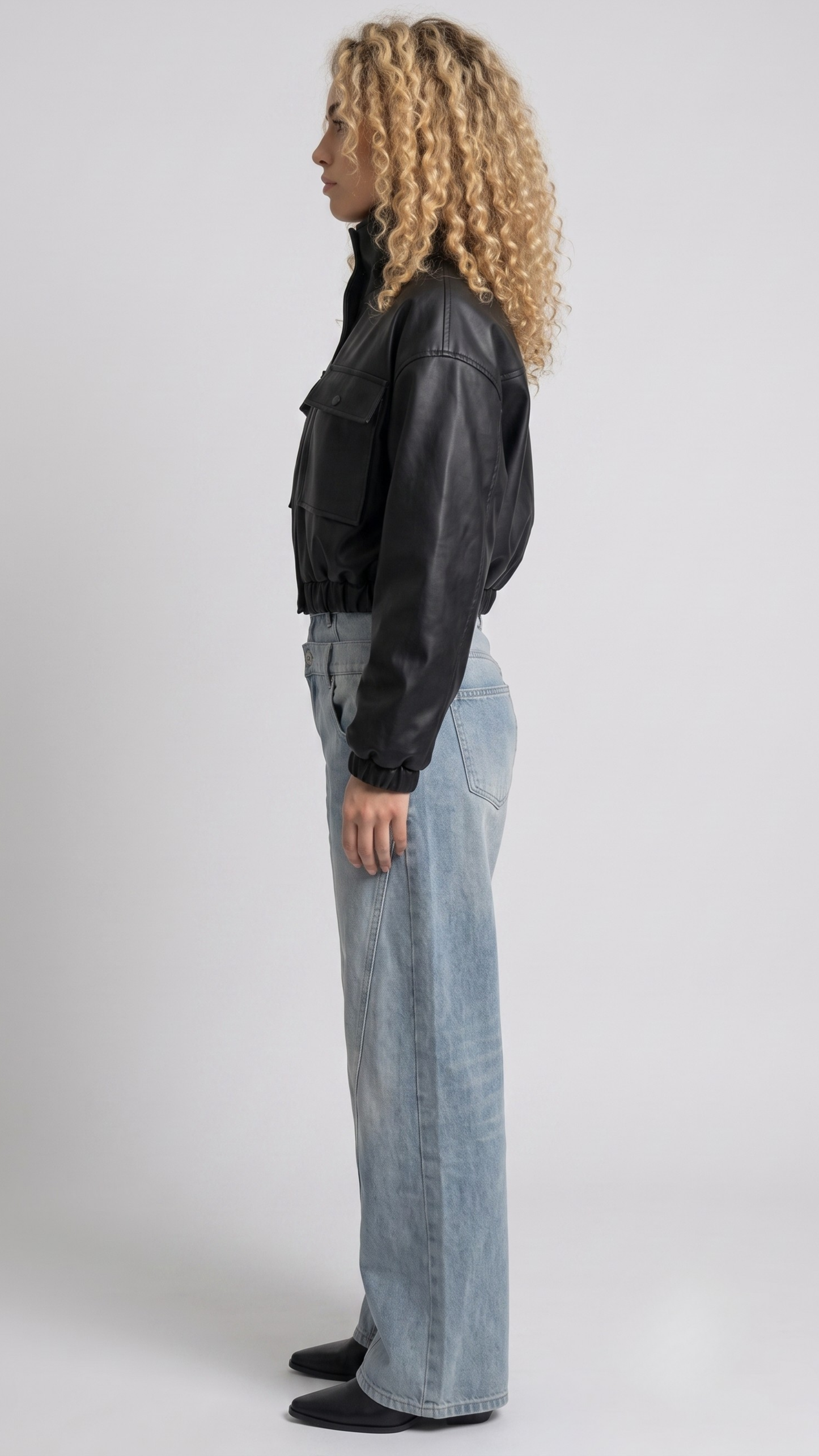 Detailed view of the sleek modern collar design, metallic hardware, and minimalist side pocket placement on a cropped leather jacket.
