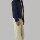 Man wearing a navy suede bomber jacket and beige pants on a gray background
