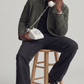 Person sitting on a stool using a vintage phone against a plain background