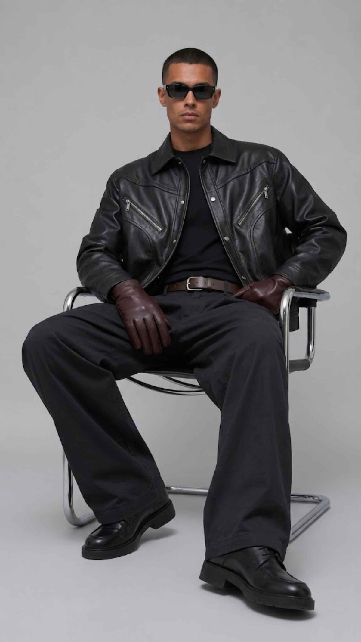 Contemporary urban fashion presentation featuring an oversized dark black leather jacket styled for a sleek monochrome outfit.