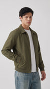 Olive green cotton blend Harrington jacket with a classic fold-down collar, antique-tone front zipper, ribbed waistband and secure side pockets, styled with a crisp white T-shirt and light blue denim for effortless urban streetwear.