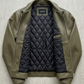 Green jacket with black quilted navy interior on a light gray background
