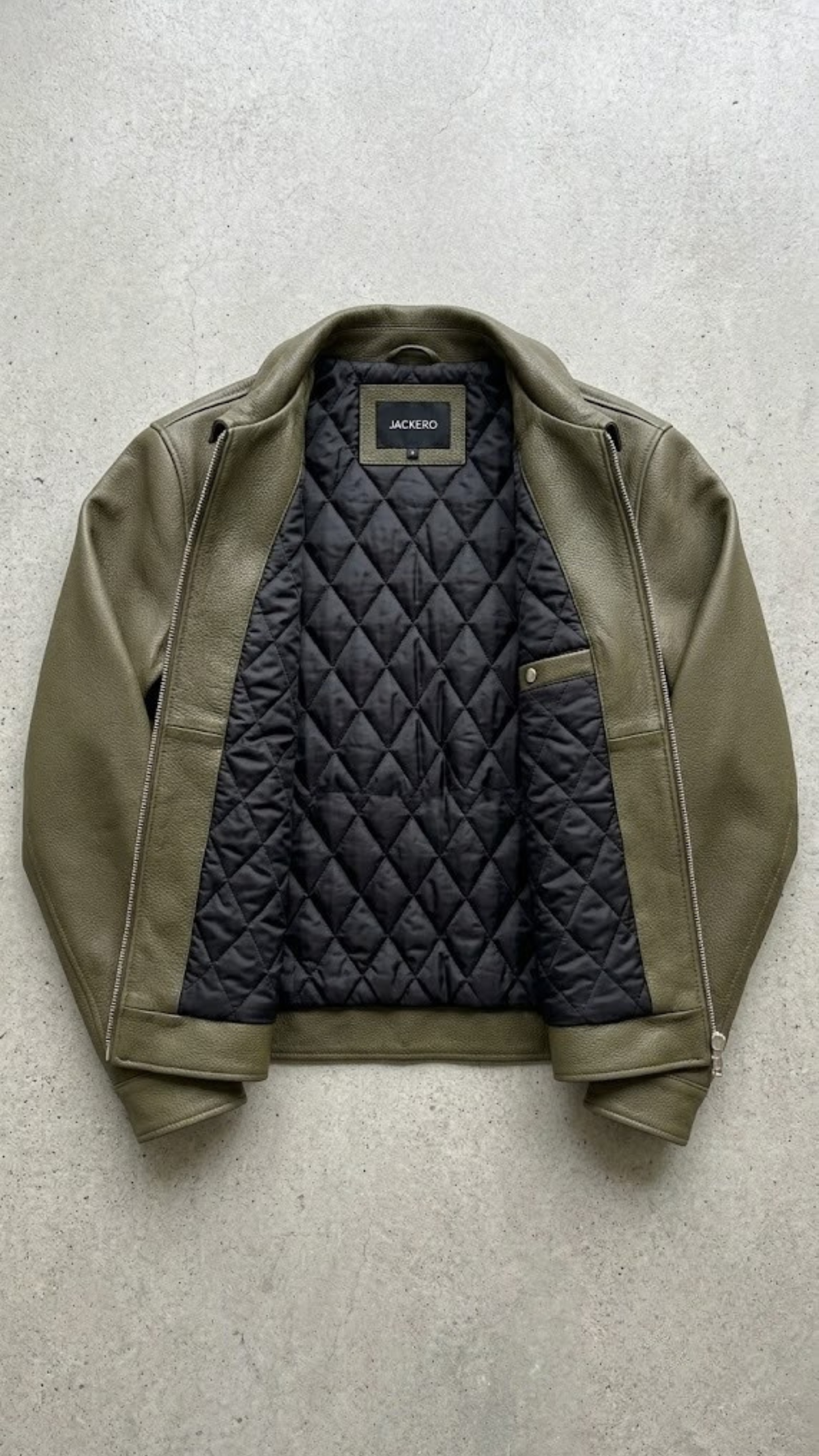 Green jacket with black quilted navy interior on a light gray background