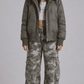 Front view of model wearing an oversized olive green puffer jacket featuring a plush fur trim hood and full zip closure