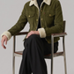Person wearing a green jacket with white fur trim, sitting on a chair against a plain background