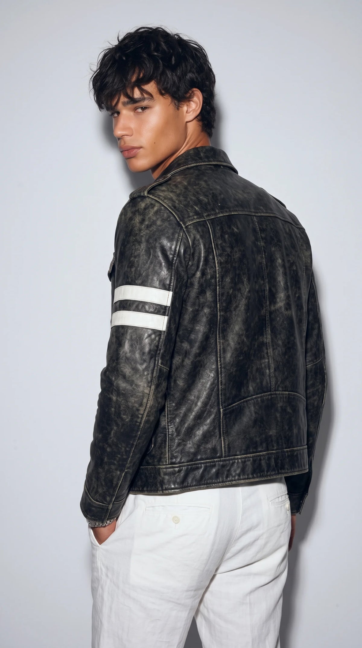 Onyx-black genuine leather jacket with buttoned shoulder epaulettes, reinforced panel seams, two white sleeve bands and a classic point collar, combining military-inspired detailing with a contemporary racing influence and a relaxed, structured silhouette.
