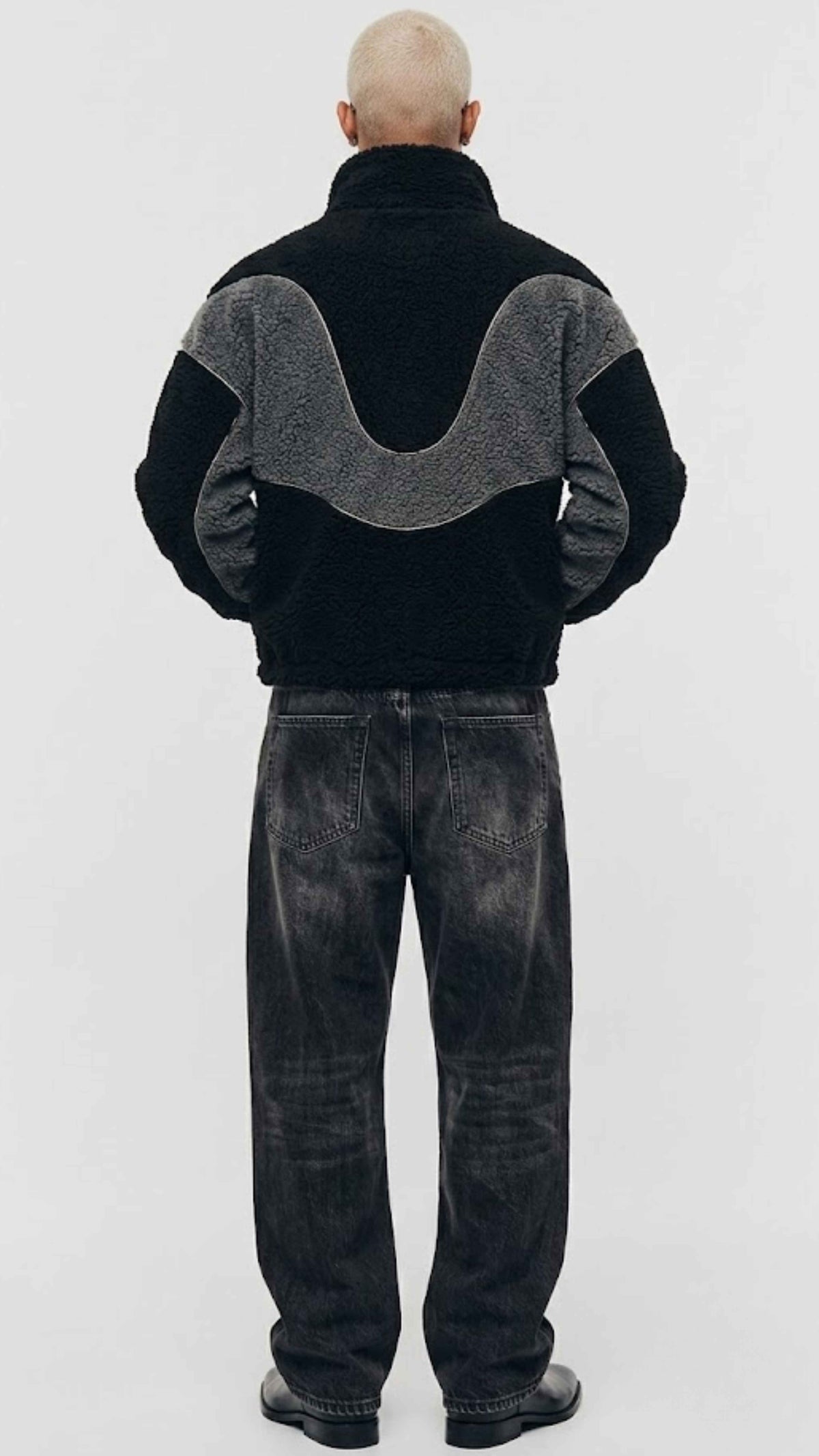 Back view showing full silhouette and structured seams of black and dark grey colorblock wool fleece coat.