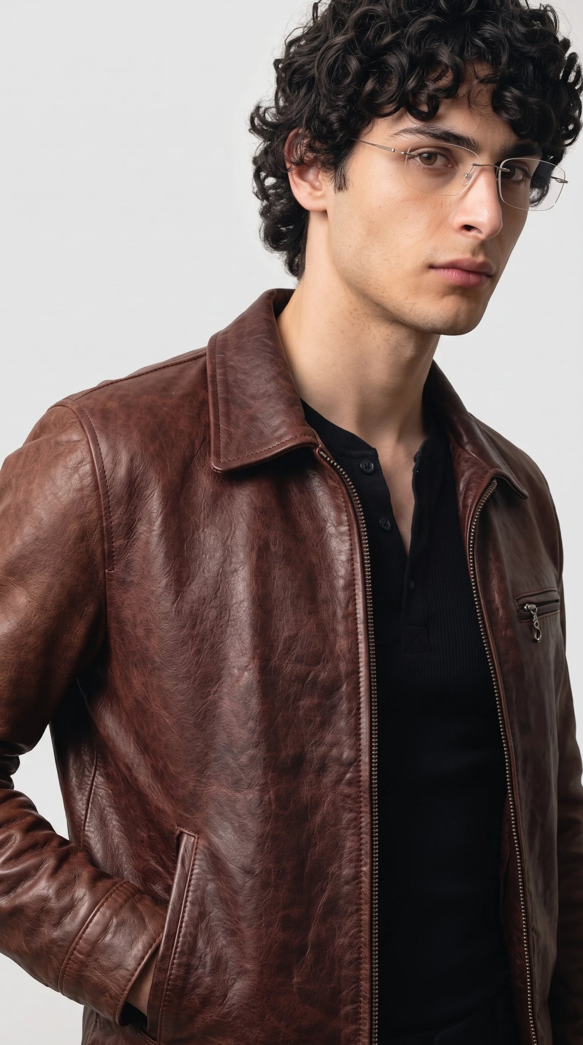 Detail of the horizontal zippered chest pocket on the left and two minimalist welt side pockets on a dark red leather jacket with premium metal zippers