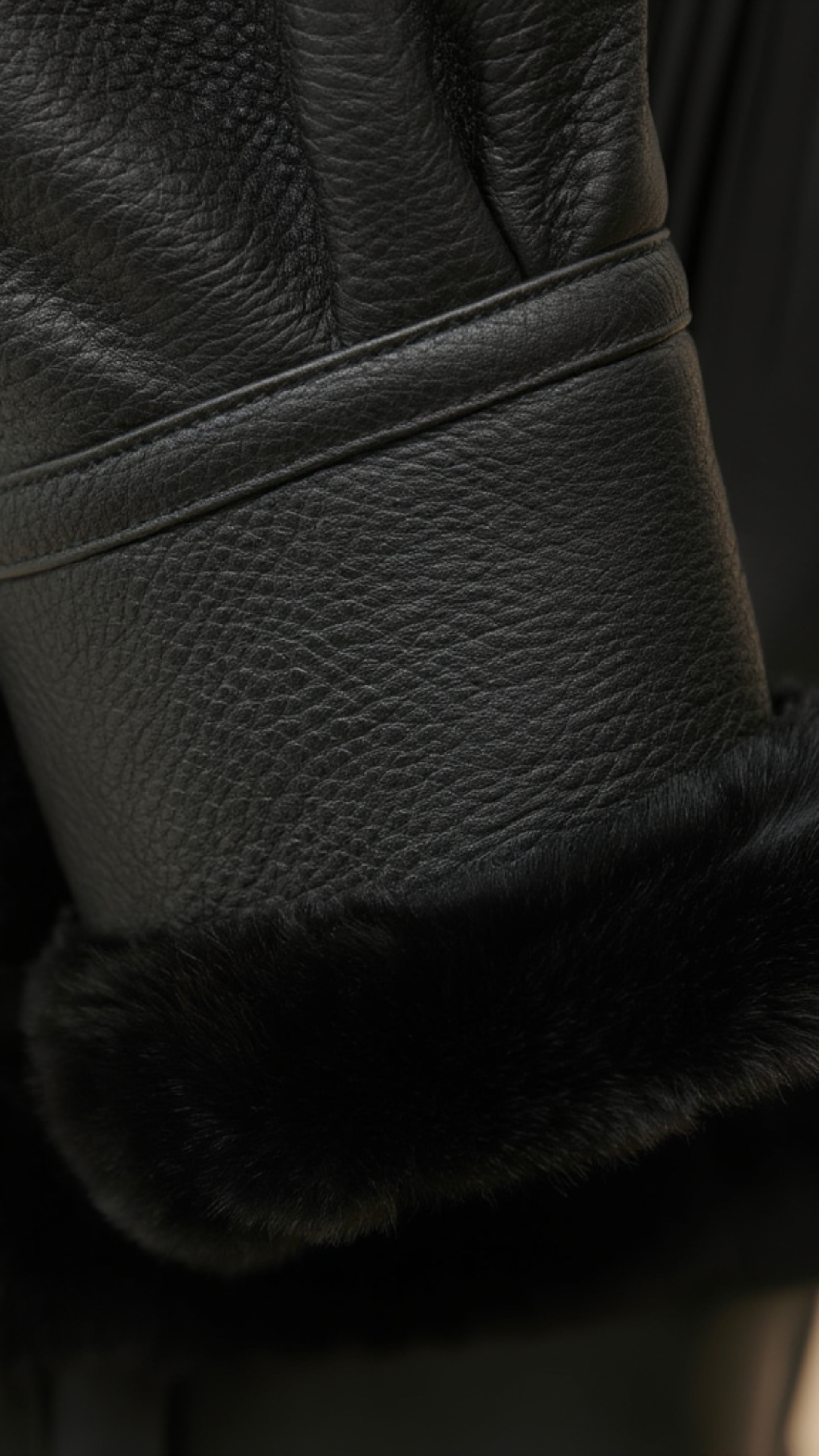 Close-up of a black leather jacket with fur lining on a dark background