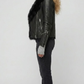 Modern streetwear styling of an all-black leather moto jacket with thick plush fur lining for winter fashion.