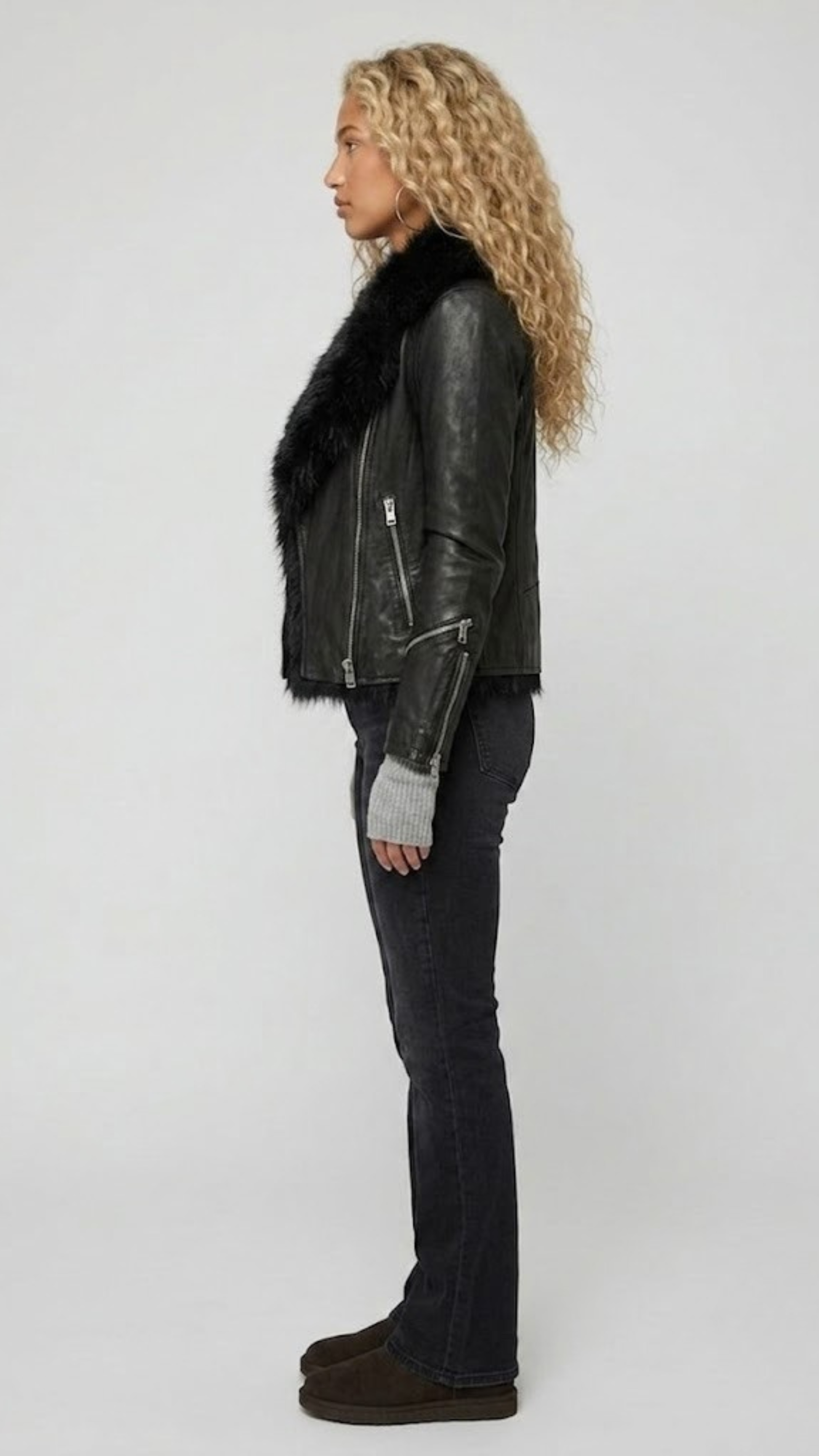 Modern streetwear styling of an all-black leather moto jacket with thick plush fur lining for winter fashion.