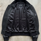 Professional studio product flat lay presentation displaying the premium black genuine leather casual bomber jacket arranged on a clean background.