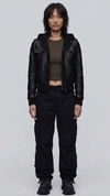 Front view lookbook photography of a model showcasing the Jackero premium black leather hooded Y2K bomber jacket styled with modern urban techwear.