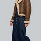 a brown leather jacket with shearling lining and blue jeans on a gray background