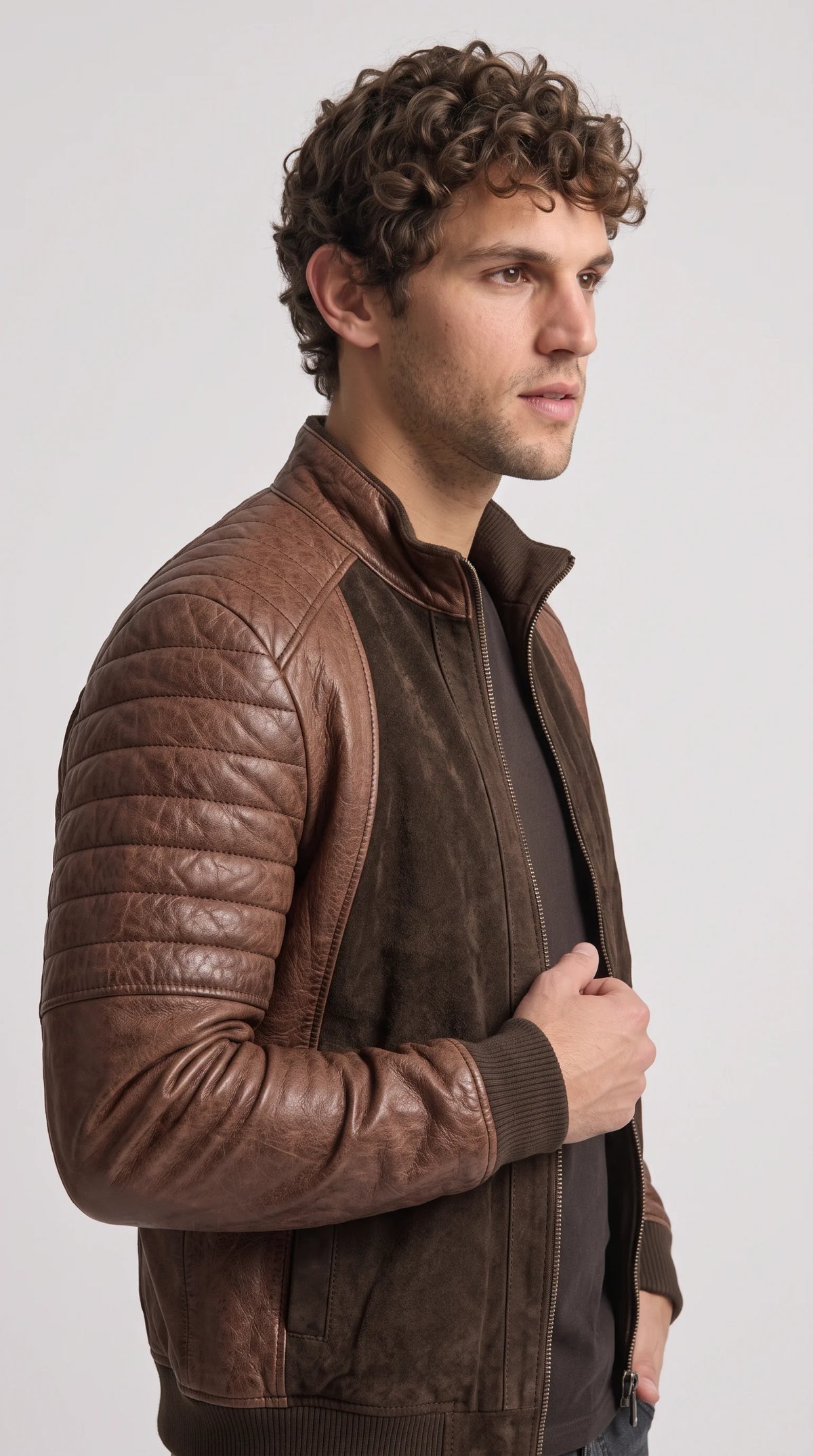 Close-up detail of a premium chocolate-brown suede and genuine leather jacket, highlighting the soft matte suede grain, carefully stitched quilted leather sleeve panels and tonal brown textures that give this contemporary outerwear design its distinctive dimensional finish.