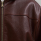 Close-up shot of the high-quality soft sheepskin leather on Jackero's dark maroon hooded bomber jacket, highlighting the luxury textured finish.
